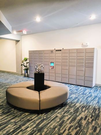 A round sofa in the middle of a room with a wall of lockers behind it.